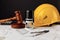 Judge wooden gavel, stamp and yellow helmet with construction plans