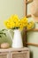 Jug with beautiful daffodils on table indoors