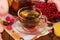 Jug and Cup of hot fruit drink on a napkin, handful of viburnum and honey, on table