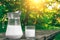 Jug and glass of cold milk on the wooden table. Fresh dairy products. Nature background.