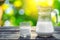 Jug and glass of cold milk on the wooden table. Fresh dairy products. Nature background.