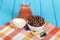 Jug of juice, yogurt, corn rings with cocoa and sesame seeds, peanuts, spoon on blue.
