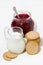 Jug of milk, cookies and sweet cranberry jam on white table, vertical top view