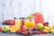 Juice in bottles, different and in a glass. Assorted berries and fruits. Gray background. Detox food. Copy space