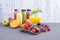 Juice in bottles, different and in a glass. Assorted berries and fruits. Gray background. Detox food. Copy space