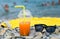 Juice with drinking straw and sunglasses on beach near sea
