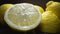 Juice drop falls from the cutted half of lemon, ripe fresh lemons are on the table, colorful isolated macro shot of
