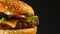 Juicy beef burger with cutlet, onion, vegetables, melted cheese, lettuce, sauce and topped sesame seeds. Isolated