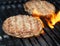 Juicy beef burgers sizzling over hot flames on the barbecue