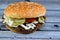 A juicy beef patty with cheese covered with sauce, crispy lettuce, fresh tomatoes, onions and pickles in a large sesame seed bun,