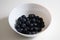 Juicy blackberries in a white bowl, berries in a white plate on a white background