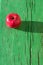 Juicy bright mature red apple on green wooden background on hard light of sunbeams with long dark shadow