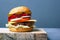 Juicy burger with cutlet, cheese and vegetables on a gray background with copy space. double cheeseburger on a wooden  plate board