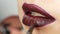 Juicy dark black red lips are made up with special brush lipstick and lip gloss, which is applied by professional makeup