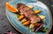 Juicy duck breast steaks with caramelized fruit, mango, apple and sauce of orange on plate over dark stone background. Hot Meat