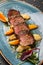 Juicy duck breast steaks with caramelized fruit, mango, apple and sauce of orange on plate over dark stone background. Hot Meat