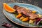 Juicy duck breast steaks with caramelized fruit, mango, apple and sauce of orange on plate over dark stone background. Hot Meat