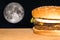 Juicy fast food hamburger on the table with moon on the background.