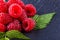 Juicy fresh natural raspberries on a dark stone background