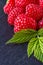 Juicy fresh natural raspberries on a dark stone background