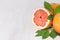 Juicy fresh round slice grapefruit closeup and green leaf on white wood background, copy space.