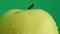 Juicy green apple in raindrops spinning on a green background