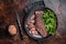 Juicy Grilled Machete skirt beef meat steak on plate with salad. Dark background. Top view