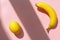 Juicy lemon and banana on trendy pink paper background in sun li