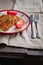 juicy meat-chicken chops and tomatoes on a white plate on a simple light linen background served with a fork and knife