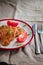 juicy meat-chicken chops and tomatoes on a white plate on a simple light linen background served with a fork and knife