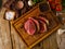 Juicy meat steaks with seasonings on a wooden cutting board on a wooden background. Low angle view. Meat recipes, cookbook, food