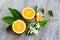 Juicy Orange cut in two parts and neroli, flowers of orange tree, on rustic wood background.