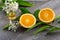 Juicy Orange cut in two parts and neroli, flowers of orange tree, on rustic wood background.