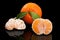 Juicy orange mandarin and two half peeled mandarin on pure black background.