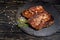 Juicy piece of fried meat lies on a stone plate against a black wooden table