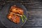 Juicy piece of fried meat lies on a stone plate against a black wooden table