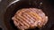 Juicy piece of grilled meat frying on pan close up. Frying pan is shaking