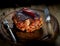 Juicy piece of pork, pepper, noh and fork on a wooden background