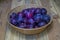 Juicy plum basket on wooden table in fresh farm garden