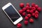 Juicy raspberries on black shale and phone