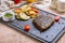Juicy Ribeye steak on black stone with grilled vegetables and pesto sauce