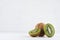 Juicy ripe green kiwi with wet slice section on white wood background.