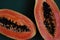 juicy ripe papaya halves on green background, tropical fruit close-up