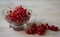 Juicy and ripe red currants in a small glass bowl, a cup stands on a light wooden background. Nearby are several branches of