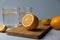 Juicy sliced â€‹â€‹lemon lies on a wooden board, next to glasses with water stand on a blue background