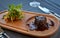 Juicy steak dish on wood plate with some greens on side in restaurant.