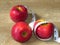 Juicy sweet ripe red summer autumn fruit. Three apples and  a centimeter tape measure on oak wood background.