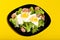 Juicy tasty healthy breakfast: fried eggs with broccoli cabbage and sausages on a black glossy plate on a yellow