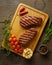 Juicy and tender two ketogenic top blade beefsteaks on wooden board with herbs and spices