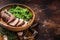 Juicy tenderloin Steak, sliced Roast beef in wooden plate with arugula. Dark background. Top view. Copy space